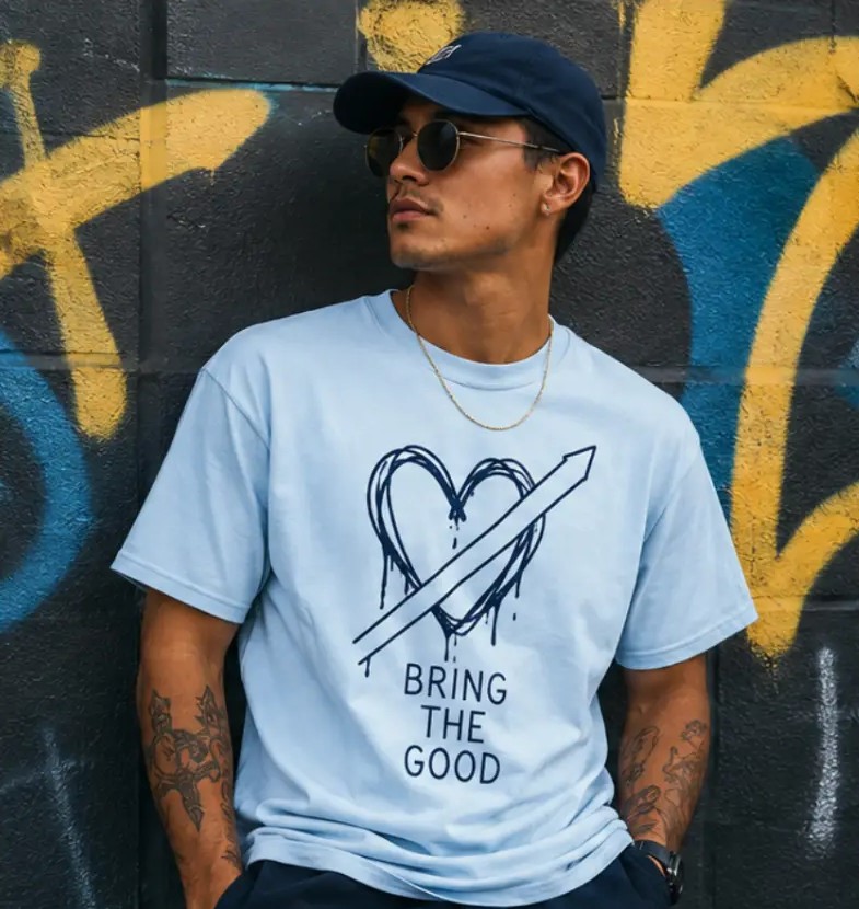Bring the Good baby blue tee worn against a graffiti wall